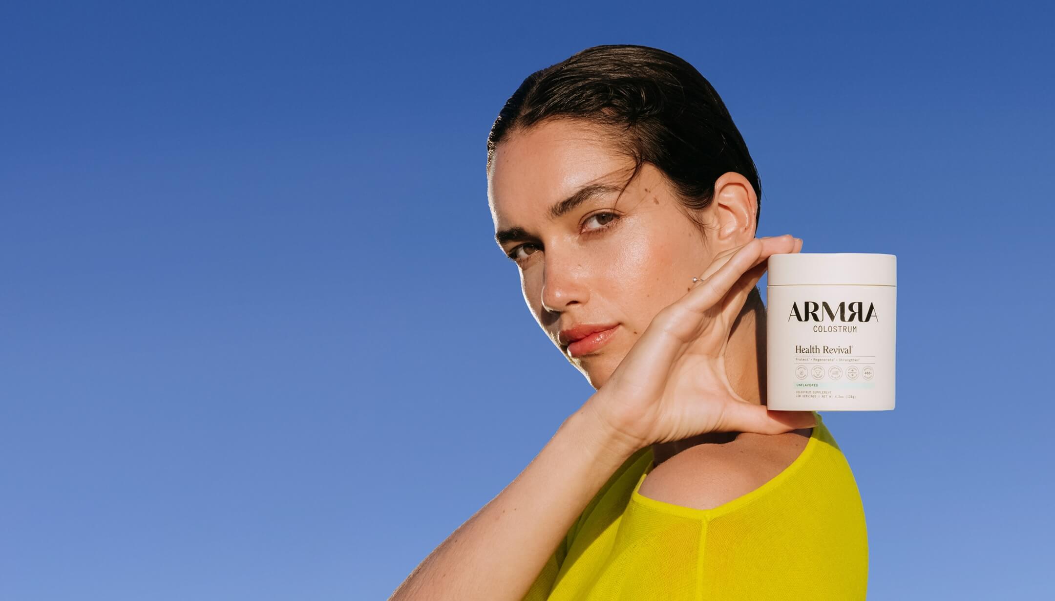 Woman holding an ARMRA jar against a vivid blue sky